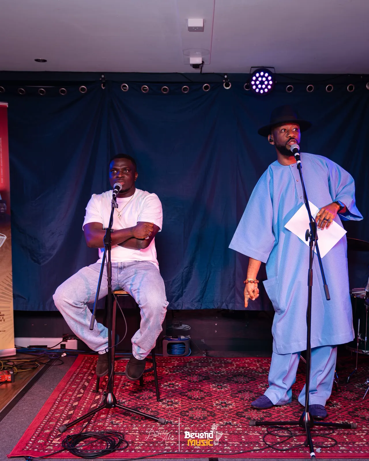 MC Crown seated at a microphone alongside another performer