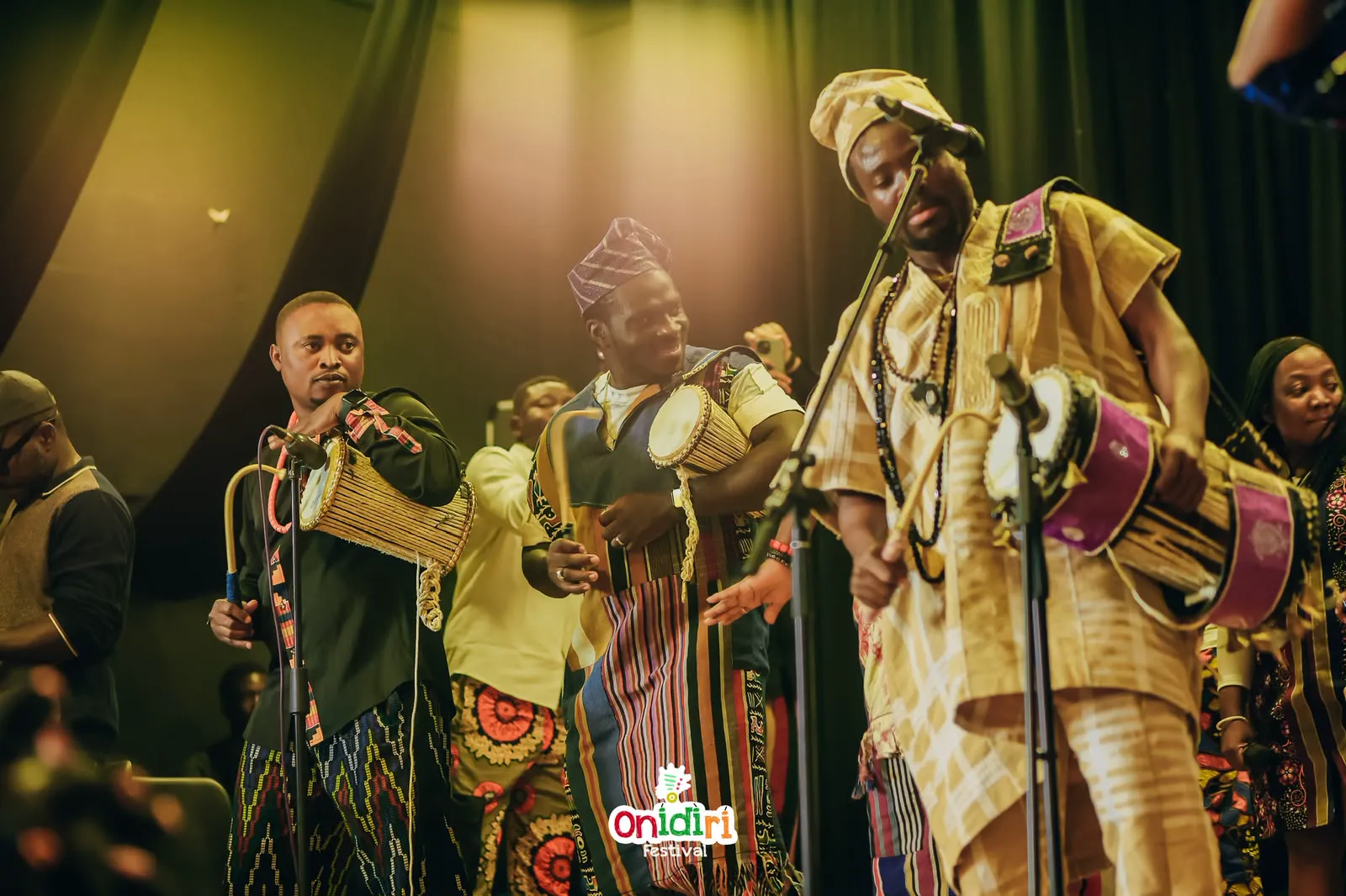MC Crown playing talking drum with a cultural percussion ensemble