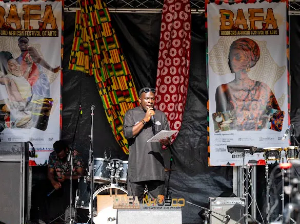 MC Crown performing with a talking drum and microphone on a festival stage