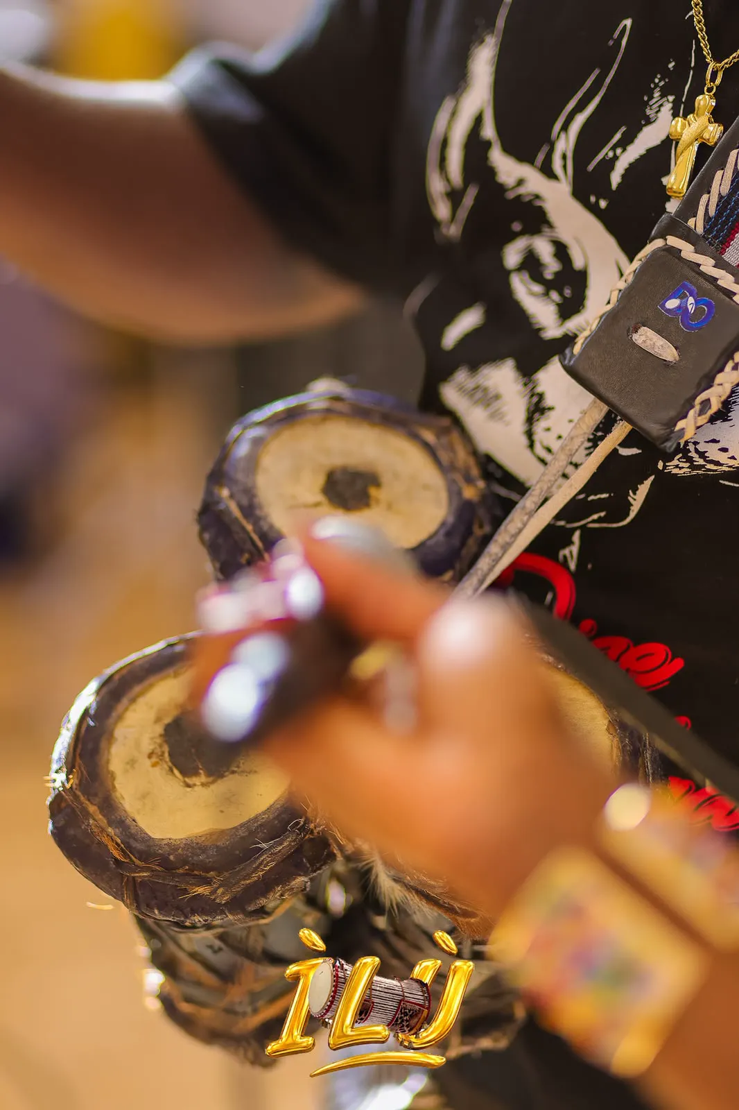 Close-up of a talking drum and curved drumstick during a performance