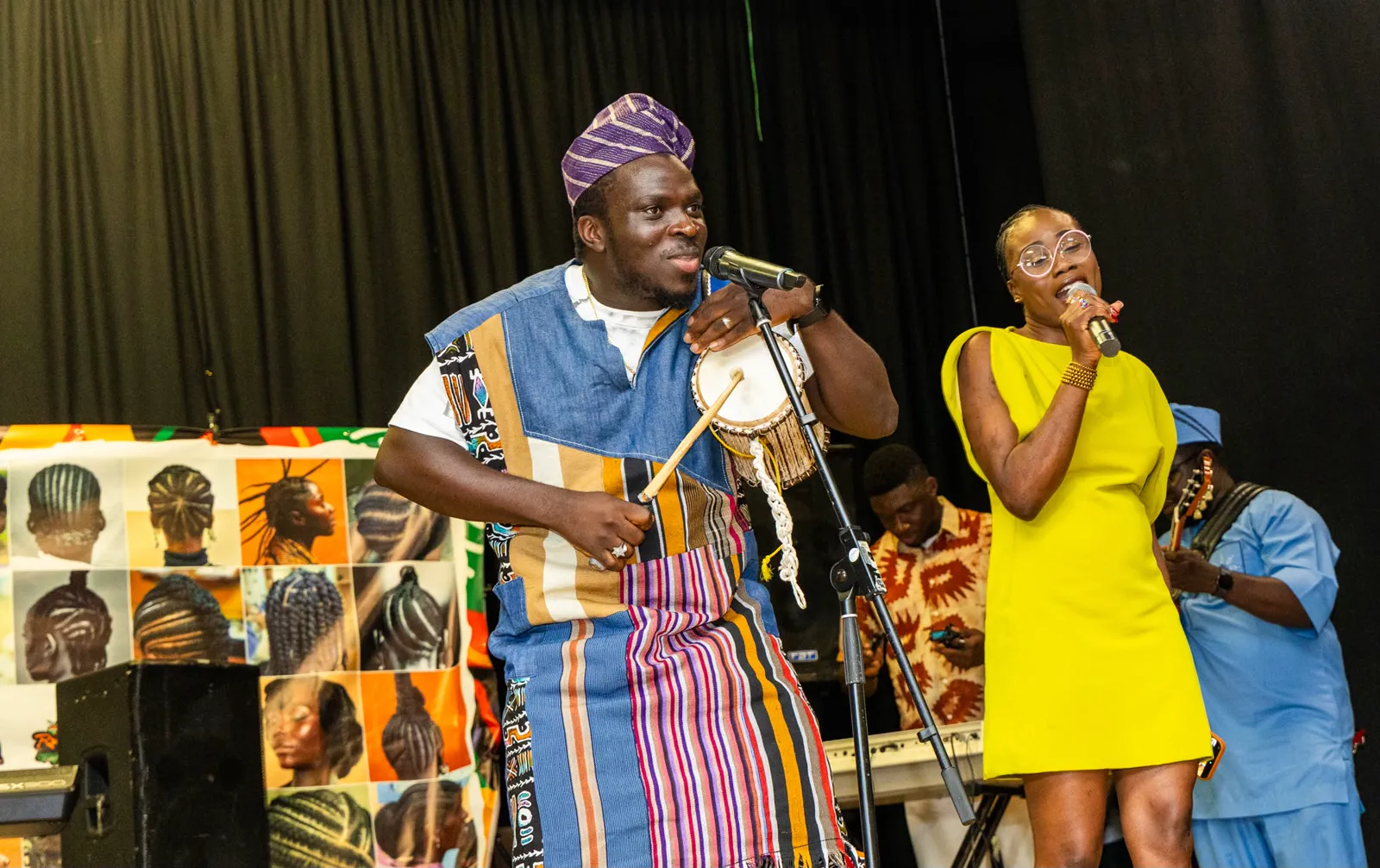 MC Crown playing a talking drum alongside a singer on stage