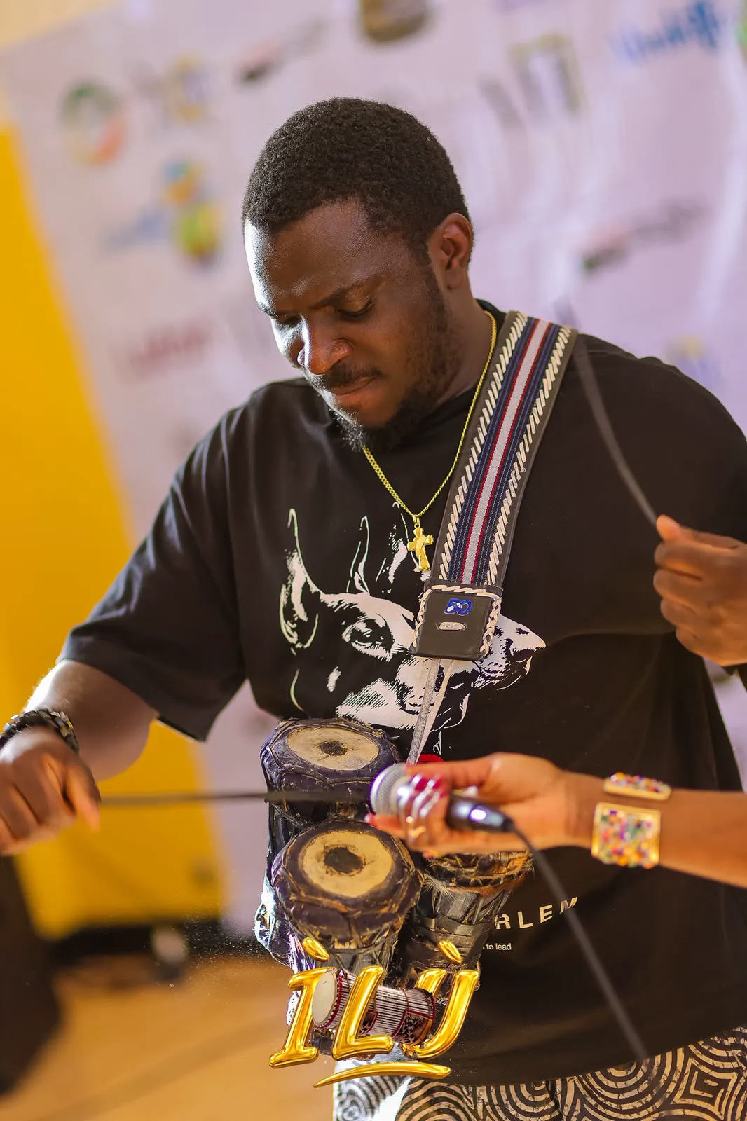 MC Crown playing a talking drum at a cultural gathering